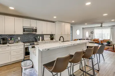 a kitchen with white cabinets and a bar with stools at 4 Mi to Dtwn Oceanside and Beach Home with Yard! in Oceanside