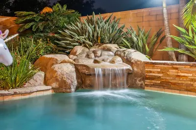 a swimming pool with a waterfall in a garden at Entire Private Home with 4 Bedrooms, Pool, Hot Tub, King Bed, Garage, Available Now in El Cajon