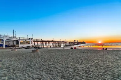 a view of a beach with a pier at sunset at North Coast Village Penthouse A306 in Oceanside