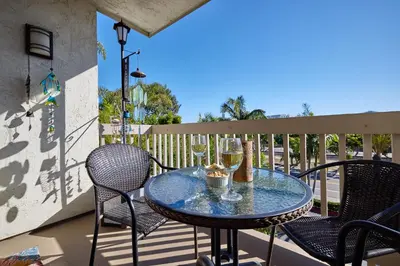 a table on a balcony with chairs and wine glasses at North Coast Village B212 in Oceanside