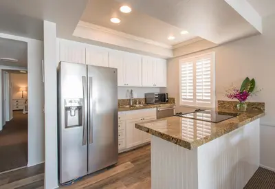 a kitchen with a stainless steel refrigerator and white cabinets at Seashore On The Sand in Carlsbad