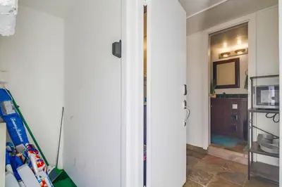 a room with a white wall and a hallway with a tv at Coastal SD Retreat Studio Pets Close to Ocean in San Diego