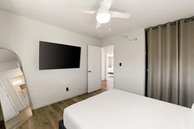 a bedroom with a white bed and a flat screen tv at Casa Malta Spa and Pool in San Diego