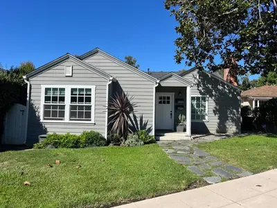 a white house with a door and a yard at La Jolla Beach Cottage in San Diego