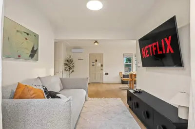 a living room with a couch and a tv on a wall at Designer Oasis with Hot Tub Firepit BBQ Sleeps 6 in San Diego