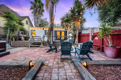 a patio with chairs and a fence with palm trees at Designer Oasis with Hot Tub Firepit BBQ Sleeps 6 in San Diego