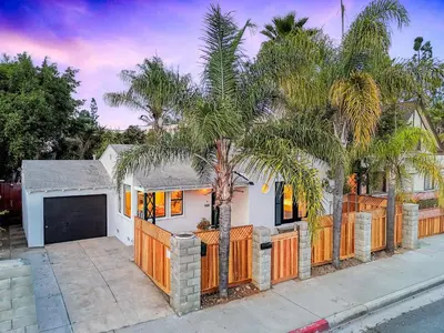 a house with a fence and a palm tree at Designer Oasis with Hot Tub Firepit BBQ Sleeps 6 in San Diego