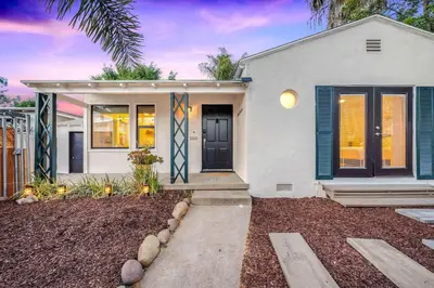 a white house with a blue door and a yard at Designer Oasis with Hot Tub Firepit BBQ Sleeps 6 in San Diego