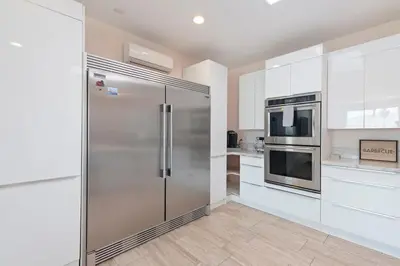 a stainless steel refrigerator in a kitchen with white cabinets at Spacious Single Level Home In Poway in Poway