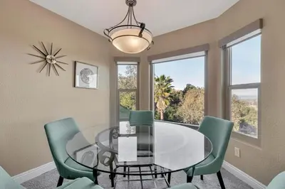 a dining room with a glass table and green chairs at The Zen House Temecula in Temecula