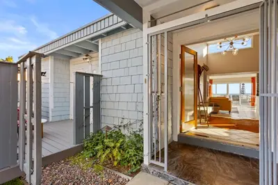 a home with a large glass door leading to a porch at Bayside Bliss House - Pool Spa Views in San Diego