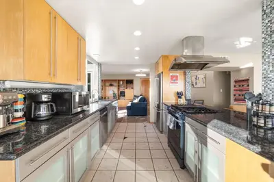 a kitchen with wooden cabinets and a counter top at Bayside Bliss House - Pool Spa Views in San Diego