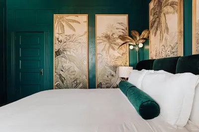 a bedroom with a white bed with green walls at Luxe Victorian Retreat • Walk to Downtown in San Diego