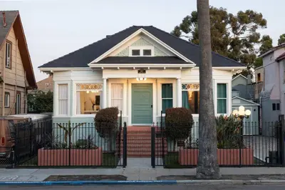a white house with a blue door on a street at Luxe Victorian Retreat • Walk to Downtown in San Diego