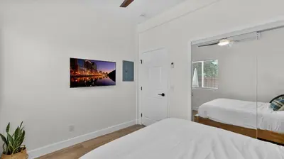 a white bedroom with two beds and a painting on the wall at Central Spot - 4 Min to Waterpark, Dining & Shops in Vista