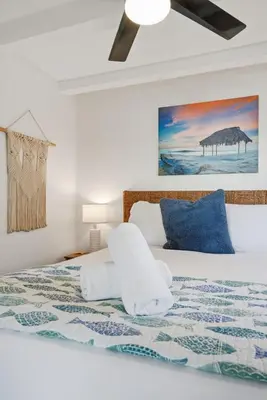 a white bedroom with a bed with blue pillows at Oceanview Mission Beach Compound, Balcony, Patio, Fire Pit, BBQ, Steps to Sand in San Diego