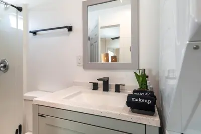 a white bathroom with a sink and a mirror at Artist micro-villa with kitchen, firepit & theater in San Diego