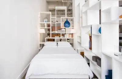 a row of beds in a room with white shelves at Historic Gaslamp Loft with Peloton Bike and Roof Deck in San Diego