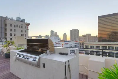 a grill on a rooftop with a view of a city at Historic Gaslamp Loft with Peloton Bike and Roof Deck in San Diego