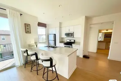 a kitchen with white cabinets and bar stools at Stylish 2BR Foothill Escape in Irvine in Lake Forest