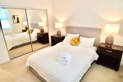 a bedroom with a white bed with a large mirror at Stylish 2BR Foothill Escape in Irvine in Lake Forest