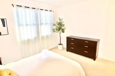 a bedroom with a bed and a dresser with a tree in it at Stylish 2BR Foothill Escape in Irvine in Lake Forest