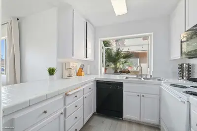 a kitchen with white cabinets and a black dishwasher at Coastal Villas Walk to the Beach 3 Homes Villa in San Diego