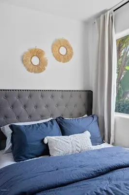 a bed with blue pillows and two mirrors on the wall at Coastal Villas Walk to the Beach 3 Homes Villa in San Diego
