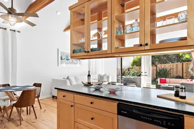 a kitchen with wooden cabinets and a table with chairs at Laguna Beach Coastal Cottage in Laguna Beach