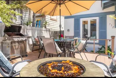 a patio with a table and an umbrella and a grill at Roswitha's Blue Wave Cottage in San Diego