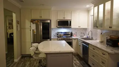 a kitchen with white cabinets and a marble counter top at Terrific 3-bedroom house with AC in Oceanside in Oceanside