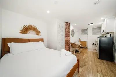 a bedroom with a bed and a kitchen with a refrigerator at Boho Little Italy Studio with Patio in San Diego