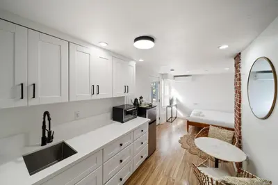 a kitchen with white cabinets and a sink and a table at Boho Little Italy Studio with Patio in San Diego