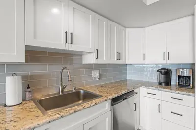 a kitchen with white cabinets and a stainless steel sink at Hawaiian Style Beachfront on Beach Road in Dana Point