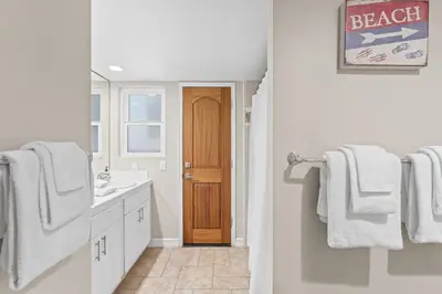 a bathroom with a sink and a door with towels at Hawaiian Style Beachfront on Beach Road in Dana Point