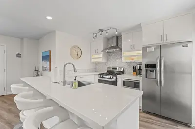 a kitchen with white cabinets and a stainless steel refrigerator at Hideaway ALL Walk to the Beach Downtown AC in San Clemente