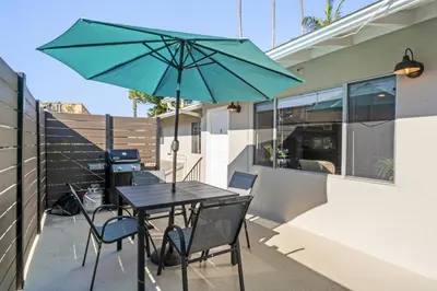 a table and chairs with a green umbrella on a balcony at Hideaway ALL Walk to the Beach Downtown AC in San Clemente