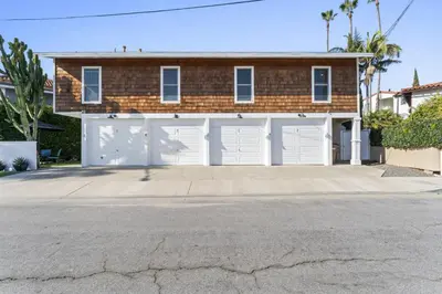 a brick house with white garage doors on a street at Hideaway ALL Walk to the Beach Downtown AC in San Clemente