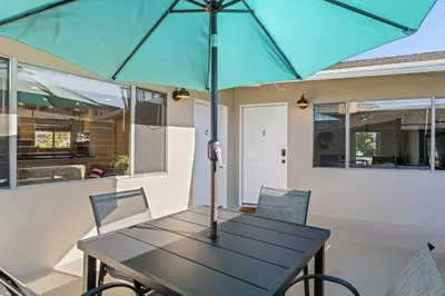 a table with a blue umbrella on a patio at Hideaway C Walk to the beach Downtown AC in San Clemente