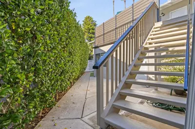 a stairway leading up to a building next to a hedge at Hideaway C Walk to the beach Downtown AC in San Clemente