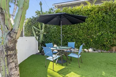 a table and chairs with an umbrella on the grass at Hideaway B Walk to the beach Downtown AC in San Clemente