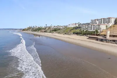 an empty beach with buildings in the background at Hideaway B Walk to the beach Downtown AC in San Clemente