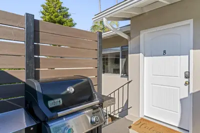 a grill in front of a fence with a door at Hideaway B Walk to the beach Downtown AC in San Clemente