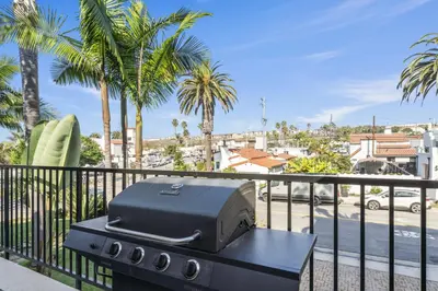 a grill on a balcony with palm trees at Coastal Duo Steps to Ole Hanson Casino and the beach in San Clemente