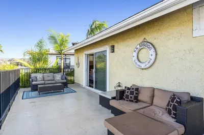 a patio with a couch and a clock on the side of a house at 4BR Beach Condo Kids Hideaway Walk to Beach Casino Ole Hanson in San Clemente