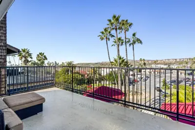 a balcony with a couch and palm trees at 4BR Beach Condo Kids Hideaway Walk to Beach Casino Ole Hanson in San Clemente