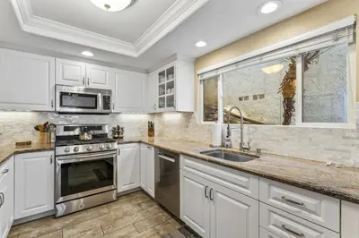 a kitchen with white cabinets and a sink and a window at Walk to the beach and Ole Hanson Casino Wedding Venues in San Clemente