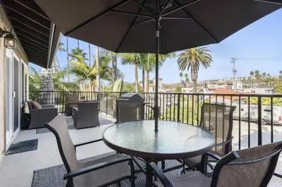 a table and chairs with an umbrella on a balcony at Tropical 2BR Retreat Walk to Beach Wedding Venues Large Deck in San Clemente