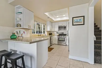a kitchen with white cabinets and a counter with stools at Walk to the Beach Wedding Venues Downtown Del Mar AC in San Clemente