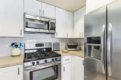 a kitchen with stainless steel appliances and white cabinets at Walk to the Beach Wedding Venues Downtown Del Mar AC in San Clemente